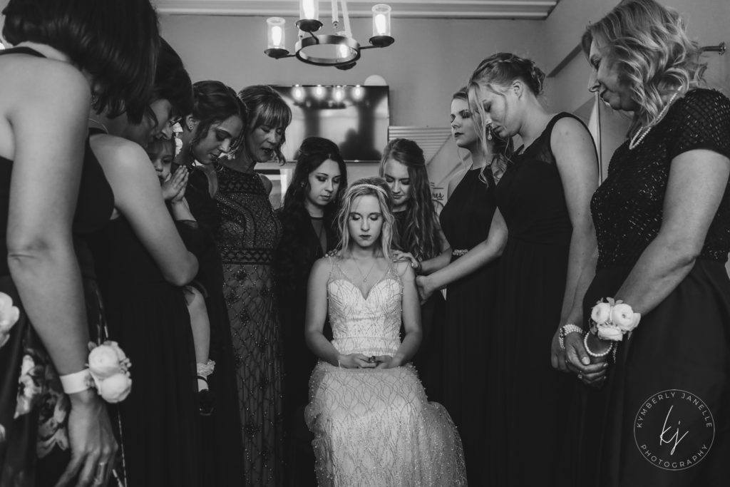 bridesmaids praying for bride